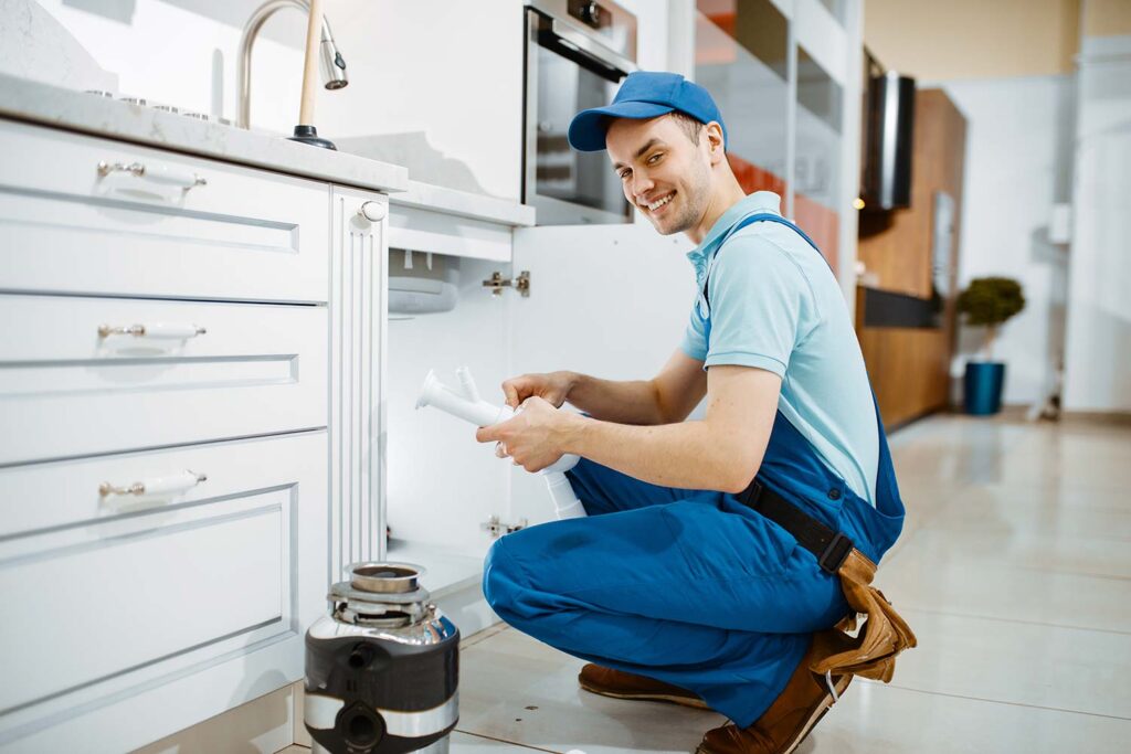 smiling Handyman replacing Disposal under sink